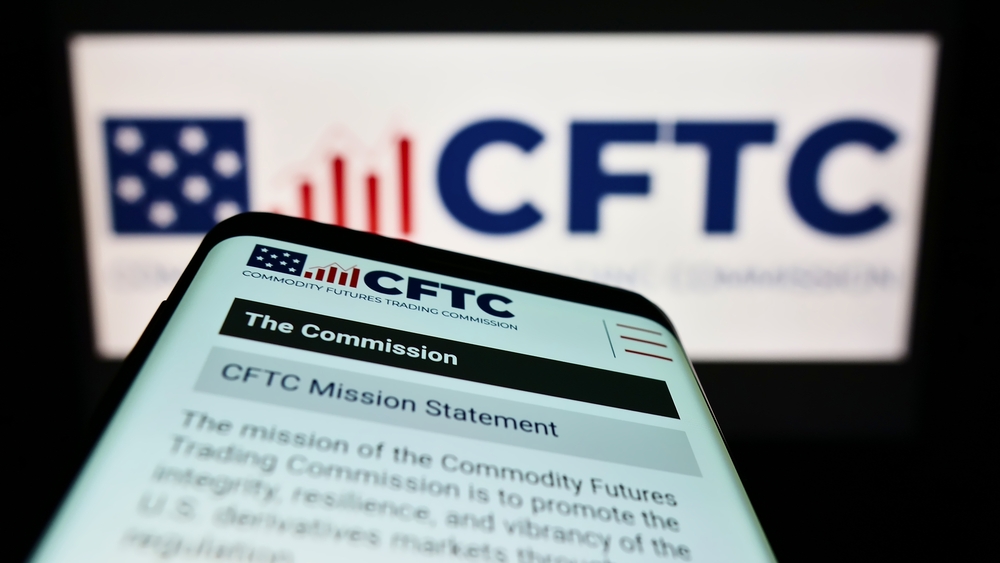 Cell phone displaying the CFTC (Commodity Futures Trading Commission) mission statement. Only the heading is visible; the rest is blurry.
